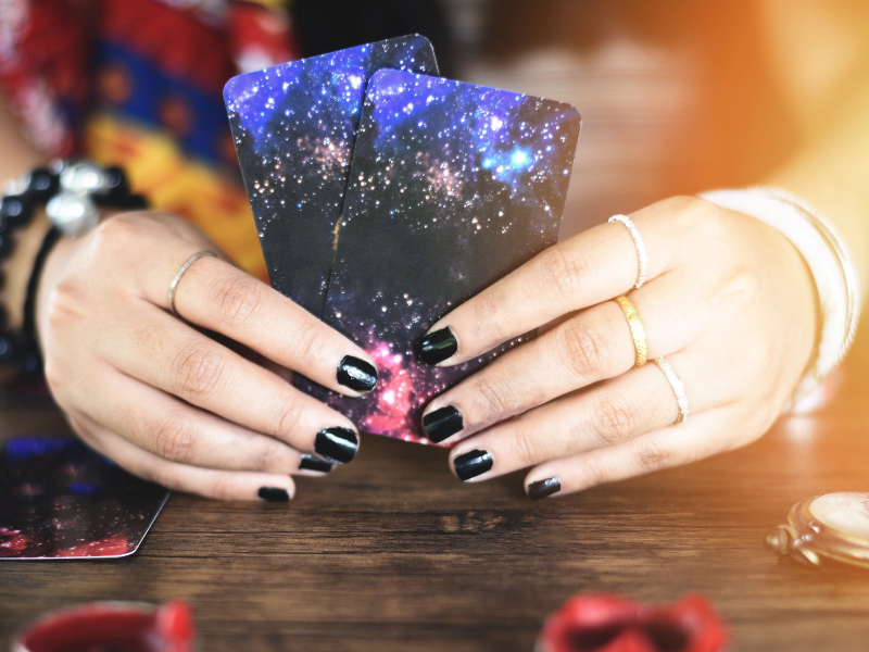 Main tirant une carte de tarot sur fond sombre - Symbolisme de la cartomancie